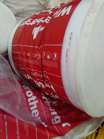 hite plastic film rolls with red printed packaging material stacked for recycling or processing.