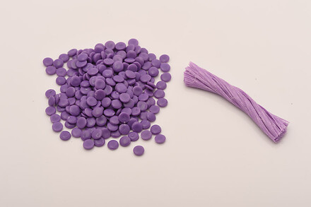 Purple plastic pellets and a bundle of purple plastic strands displayed on a white background.