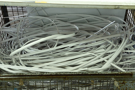 White plastic strips stored in a metal container for collection, handling, or recycling.