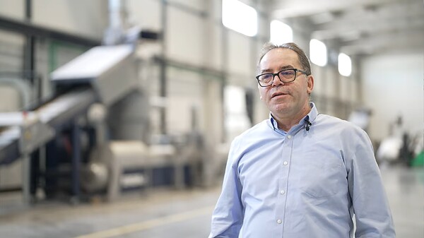 Dejan Micić, CEO of Repol standing in front of EREMA recycling equipment inside an industrial production facility.